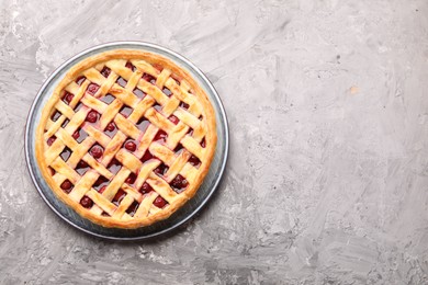 Photo of Tasty cherry pie on grey textured table, top view. Space for text