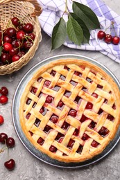 Photo of Tasty cherry pie and berries on grey textured table, flat lay