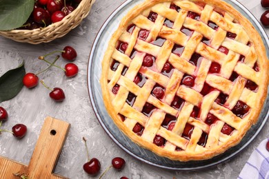 Photo of Tasty cherry pie and berries on grey textured table, flat lay