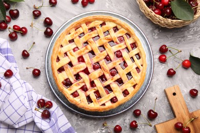 Photo of Tasty cherry pie and berries on grey textured table, flat lay