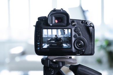 Photo of Woman on sofa in studio, focus on video camera recording her