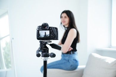 Photo of Woman on sofa in studio, focus on video camera recording her