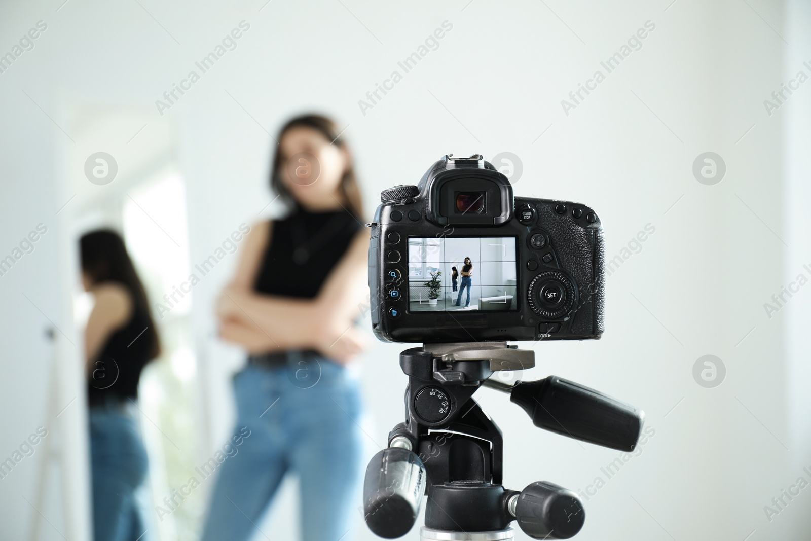 Woman near mirror in studio, focus on video camera recording her Photo of Woman near mirror in studio, focus on video camera recording her