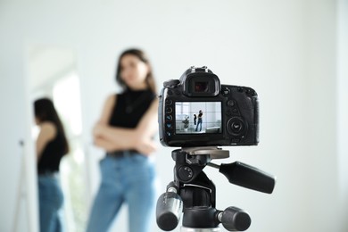 Photo of Woman near mirror in studio, focus on video camera recording her