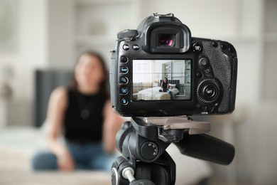 Photo of Woman sitting on bed in studio, focus on video camera recording her