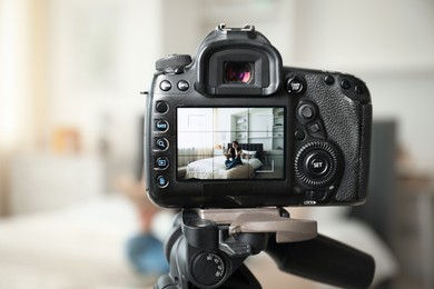 Photo of Woman reading book on bed in studio, focus on video camera recording her