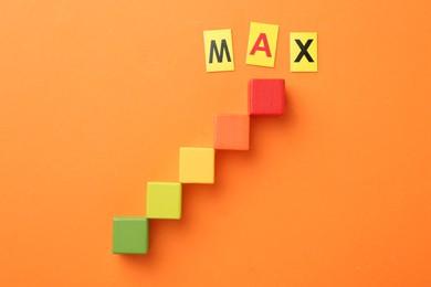 Photo of Colorful cubes and word Max on orange background, flat lay