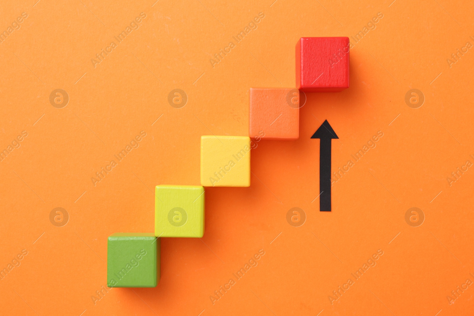 Maximum. Arrow pointing at colorful cubes on orange background, top view Photo of Maximum. Arrow pointing at colorful cubes on orange background, top view