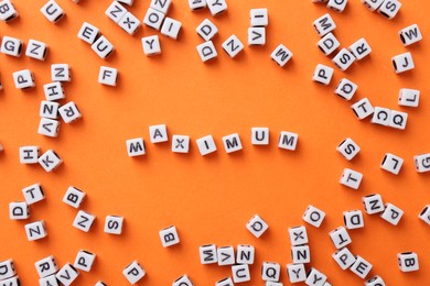 Photo of Word Maximum made of cubes on orange background, flat lay