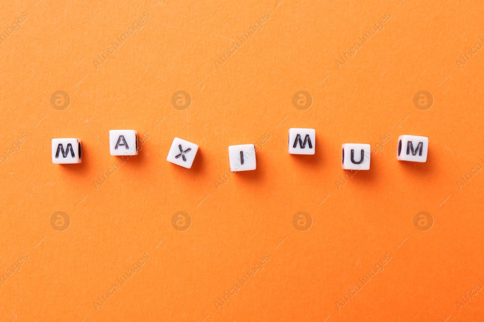 Word Maximum made of cubes on orange background, top view Photo of Word Maximum made of cubes on orange background, top view