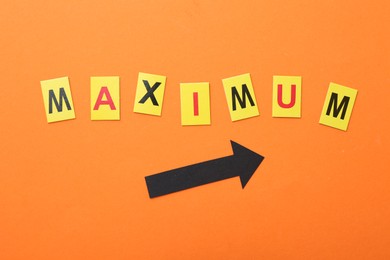 Photo of Word Maximum and arrow on orange background, top view