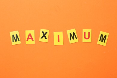 Photo of Word Maximum on orange background, top view