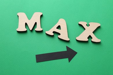 Photo of Word Max and arrow on green background, top view
