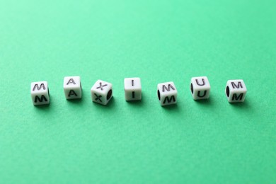 Photo of Word Maximum made of cubes on green background