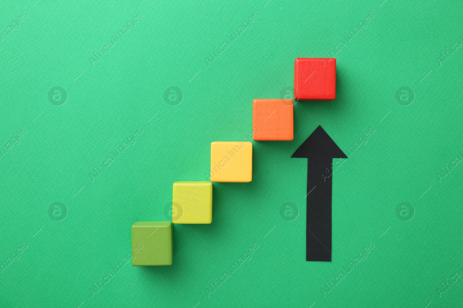 Maximum. Arrow pointing at colorful cubes on green background, flat lay Photo of Maximum. Arrow pointing at colorful cubes on green background, flat lay