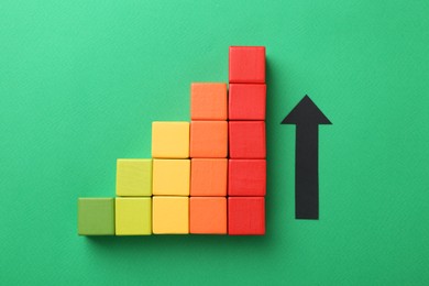 Photo of Maximum. Arrow and colorful cubes on green background, top view