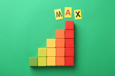 Photo of Colorful cubes and word Max on green background, top view