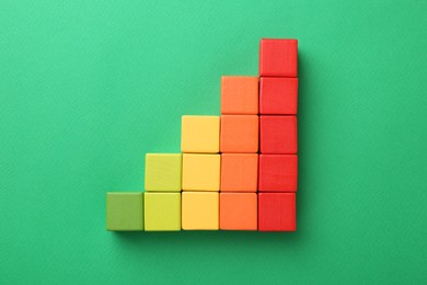 Photo of Maximum. Colorful cubes on green background, top view