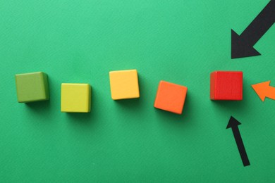 Photo of Maximum. Arrows pointing at colorful cubes on green background, flat lay