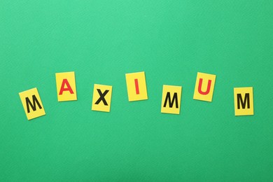 Photo of Word Maximum on green background, top view