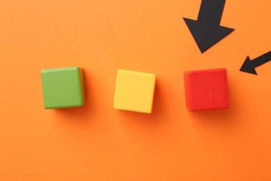 Photo of Maximum. Arrows pointing at colorful cubes on orange background, flat lay