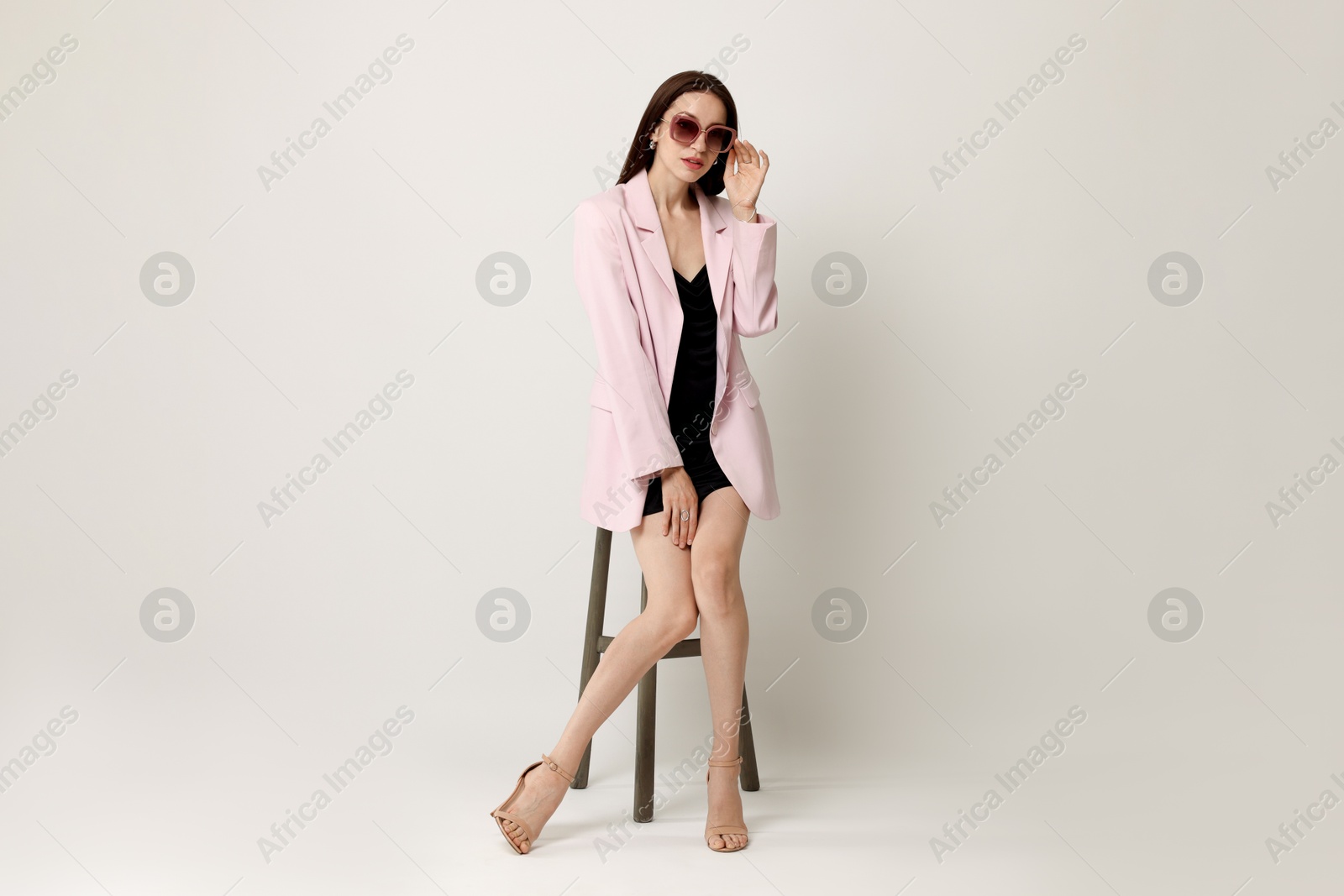 Beautiful woman in stylish outfit sitting on chair against white background Photo of Beautiful woman in stylish outfit sitting on chair against white background