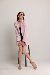 Photo of Beautiful woman in stylish outfit sitting on chair against white background