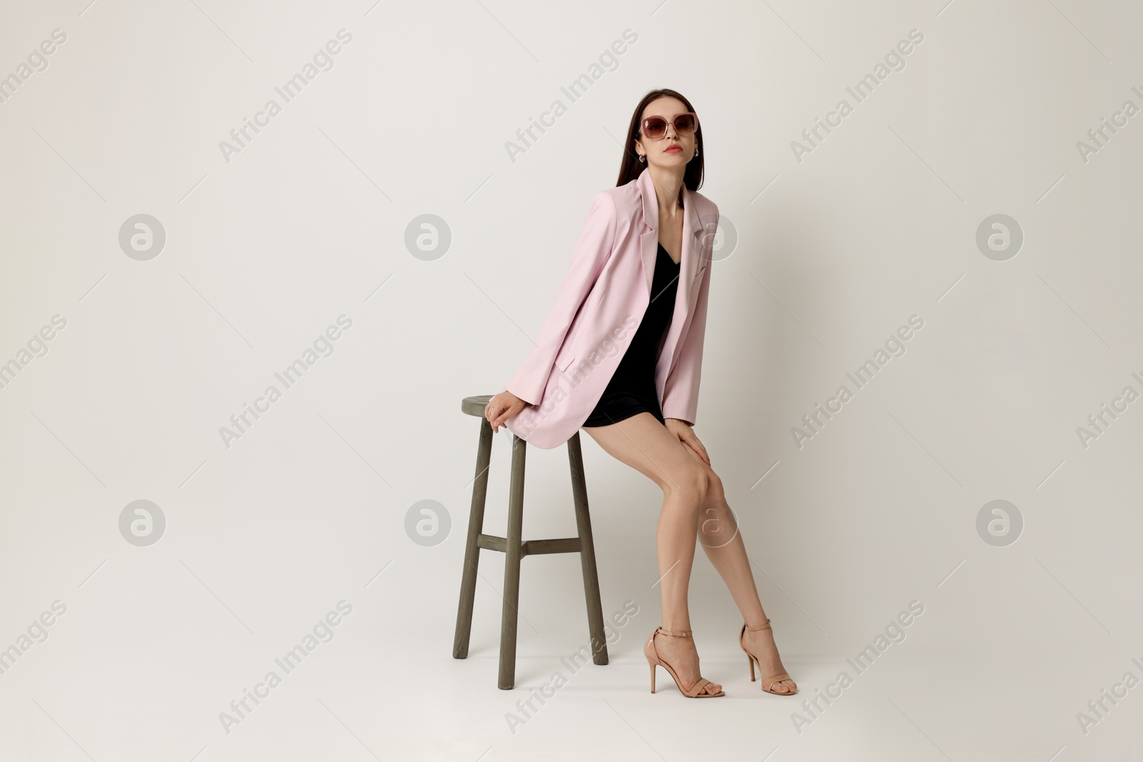 Beautiful woman in stylish outfit sitting on chair against white background Photo of Beautiful woman in stylish outfit sitting on chair against white background