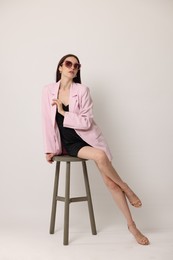 Photo of Beautiful woman in stylish outfit sitting on chair against white background