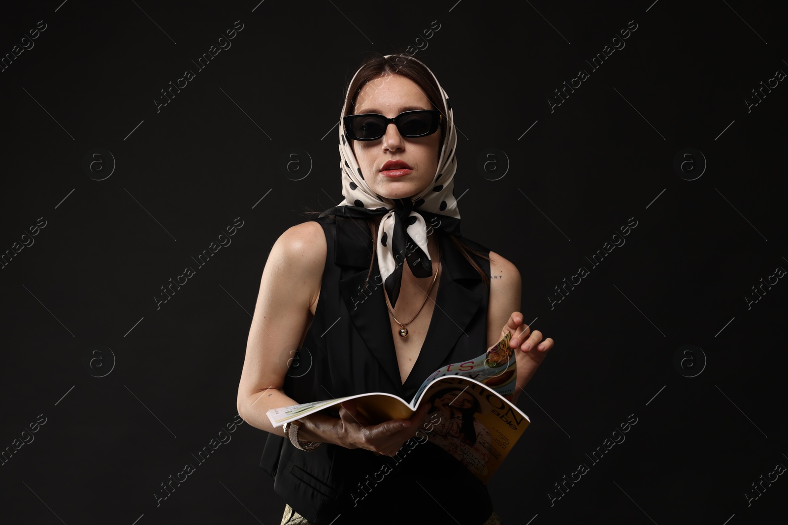 Beautiful woman in stylish outfit with fashion magazine on black background Photo of Beautiful woman in stylish outfit with fashion magazine on black background