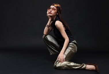 Photo of Full-length portrait of beautiful woman in stylish outfit on black background