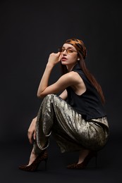 Photo of Full-length portrait of beautiful woman in stylish outfit on black background
