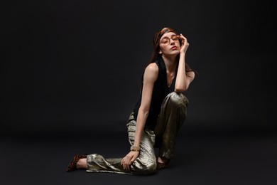Photo of Full-length portrait of beautiful woman in stylish outfit on black background