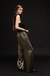 Photo of Full-length portrait of beautiful woman in stylish outfit on black background
