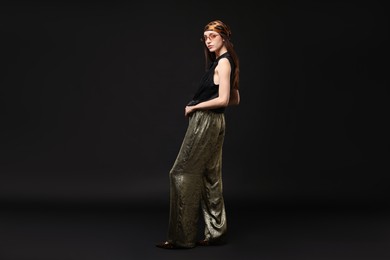 Photo of Full-length portrait of beautiful woman in stylish outfit on black background