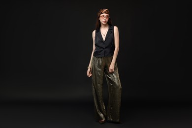 Photo of Full-length portrait of beautiful woman in stylish outfit on black background