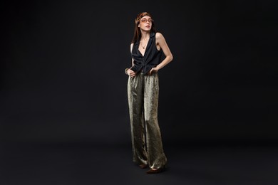 Photo of Full-length portrait of beautiful woman in stylish outfit on black background