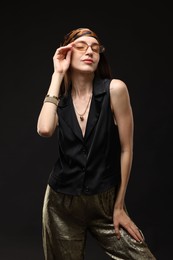 Photo of Portrait of beautiful woman in stylish outfit on black background