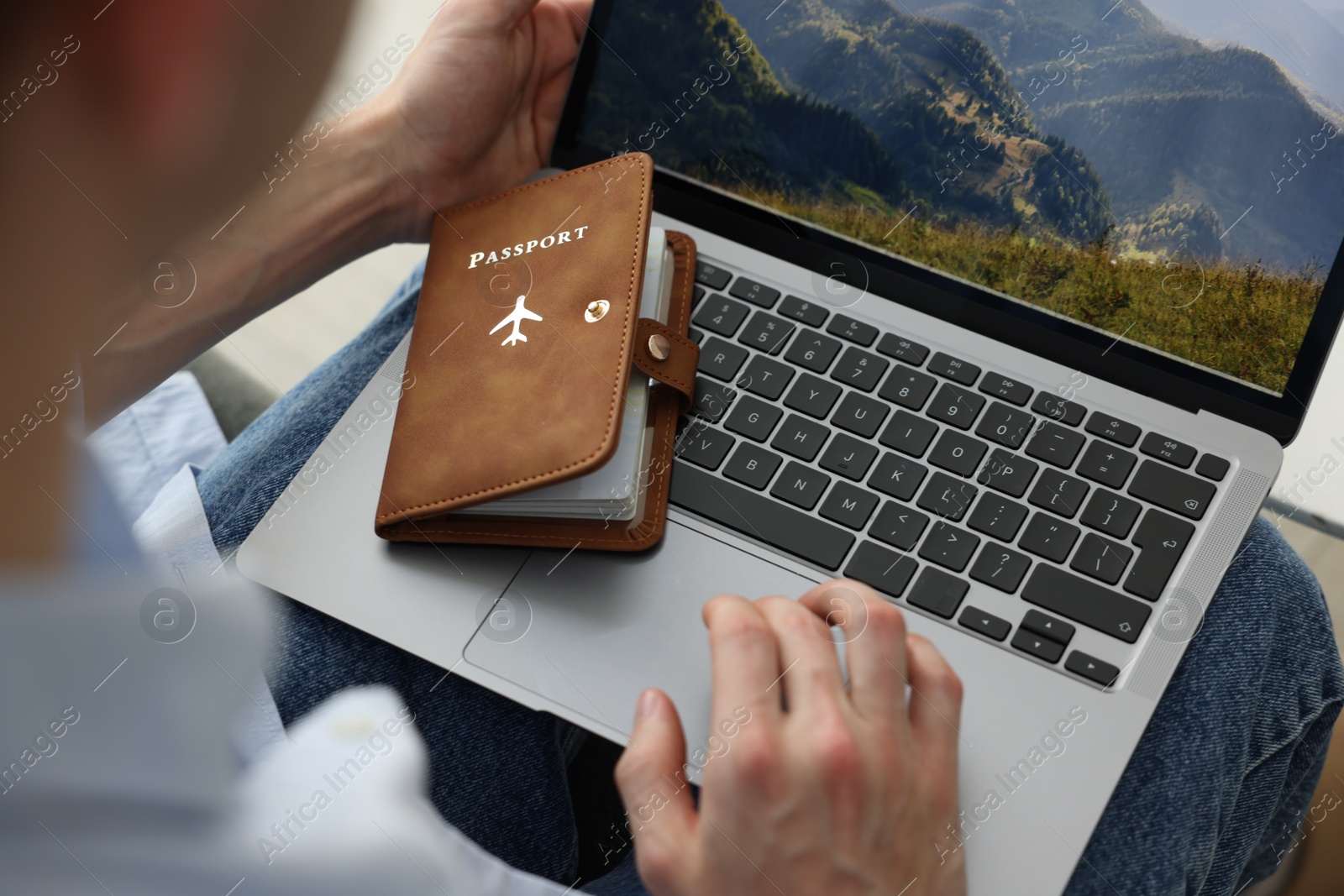 Man with passport using laptop indoors, closeup Photo of Man with passport using laptop indoors, closeup