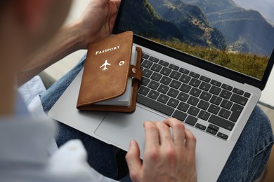 Photo of Man with passport using laptop indoors, closeup