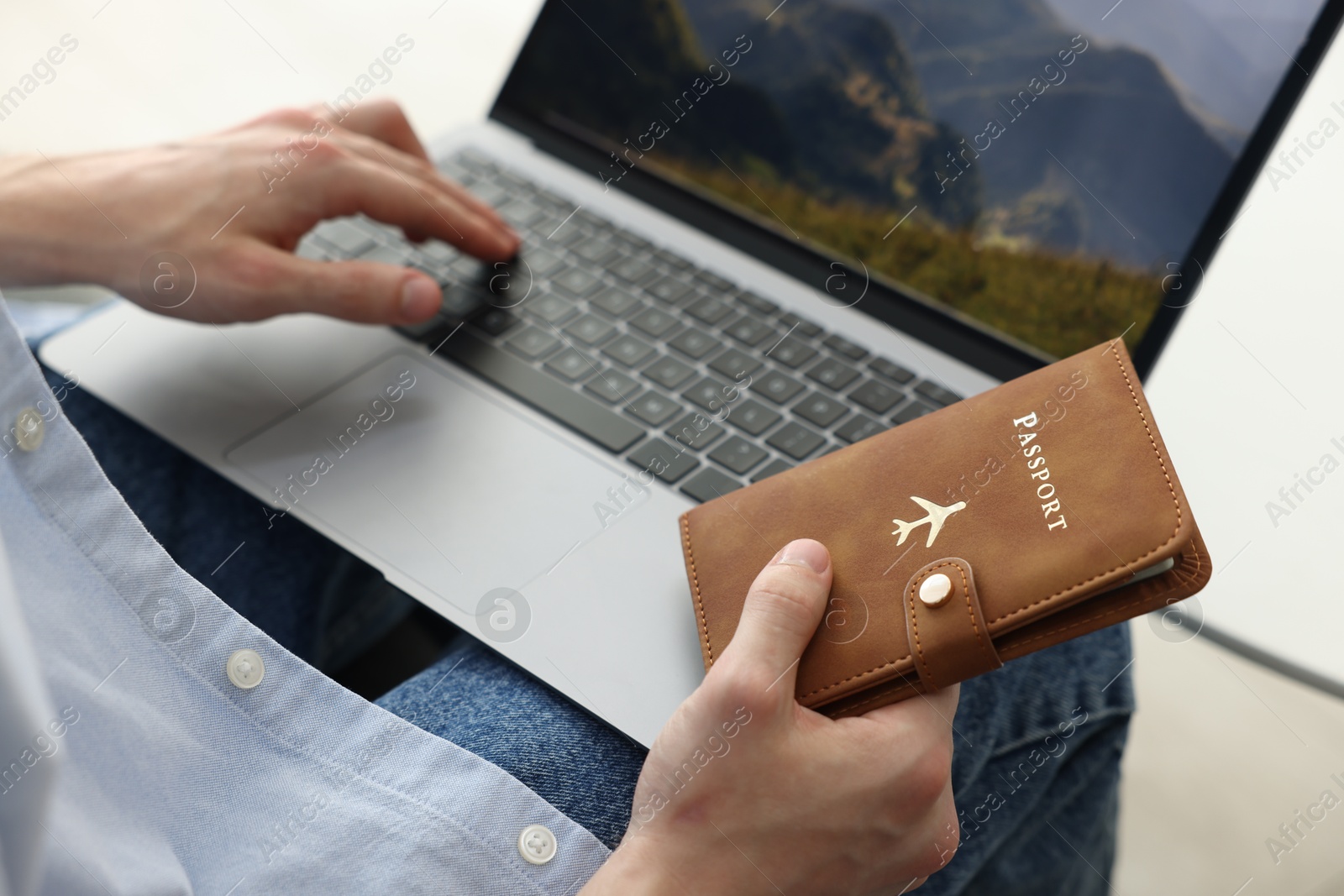 Man with passport using laptop indoors, closeup Photo of Man with passport using laptop indoors, closeup