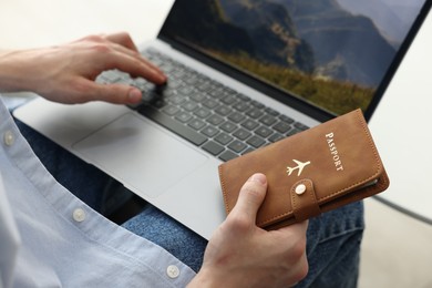 Photo of Man with passport using laptop indoors, closeup
