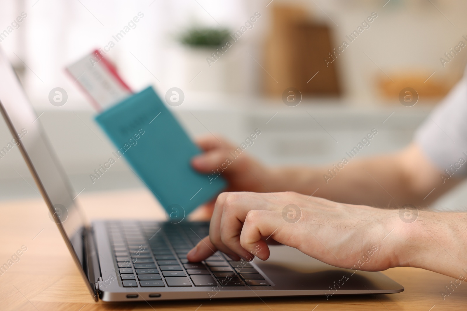 Man with passport and flight ticket using laptop at table indoors, closeup Photo of Man with passport and flight ticket using laptop at table indoors, closeup