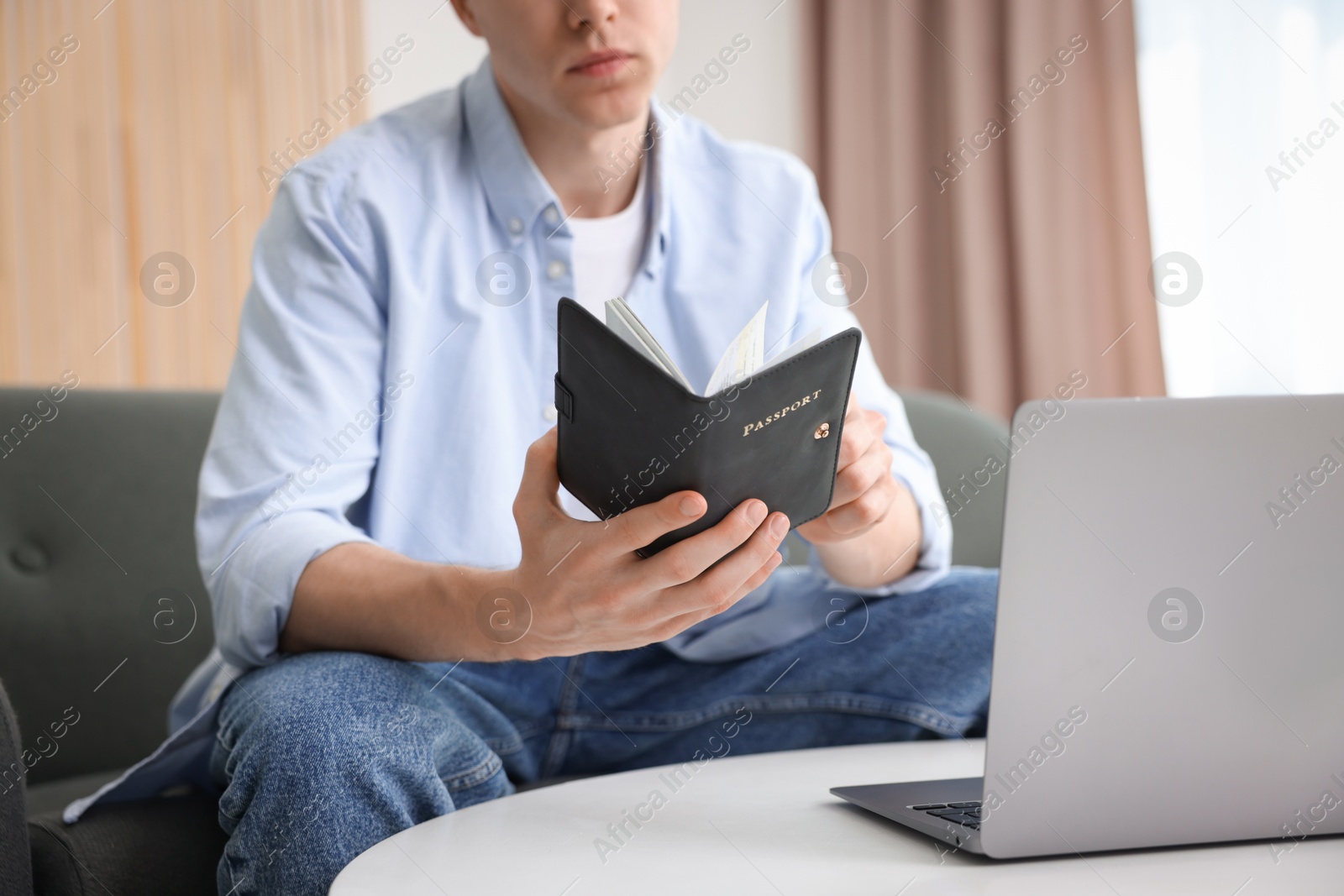 Man with passport near laptop at home, closeup Photo of Man with passport near laptop at home, closeup