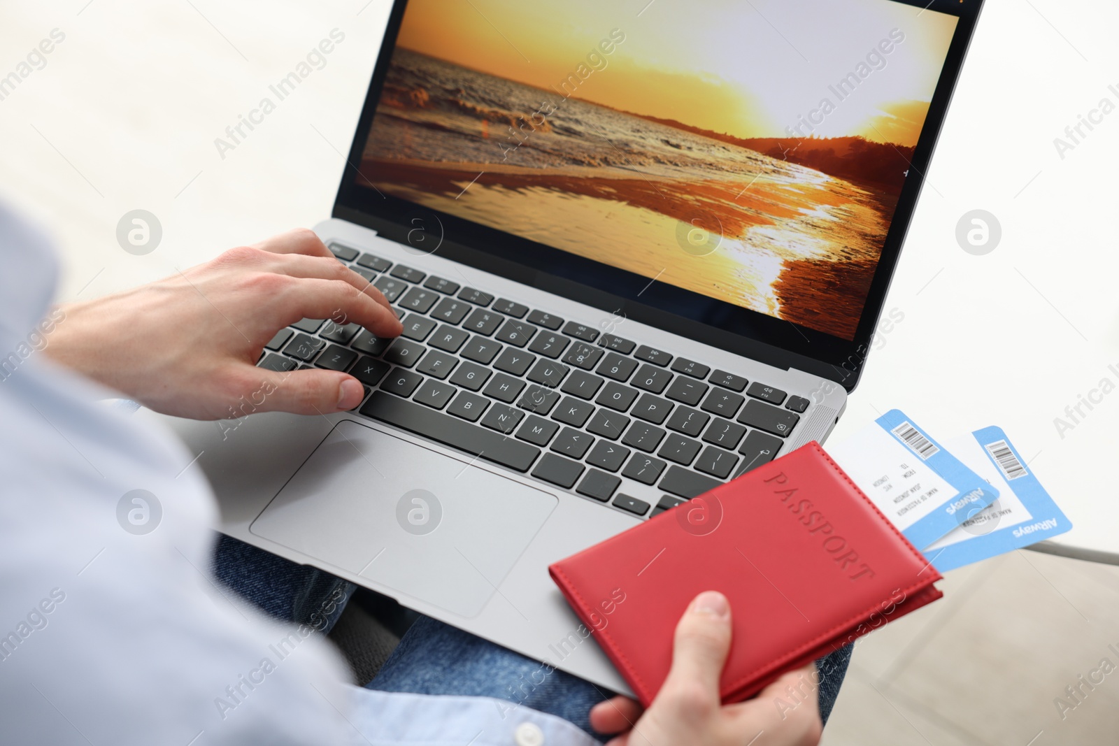 Man with passport and flight tickets using laptop at table indoors, closeup Photo of Man with passport and flight tickets using laptop at table indoors, closeup