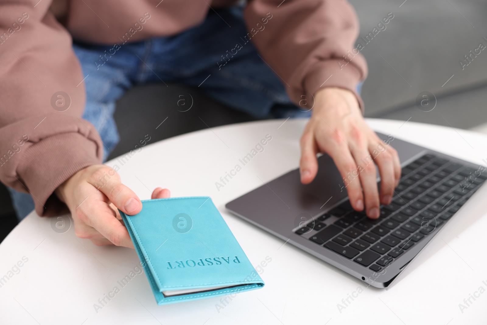Man with passport using laptop at table indoors, closeup Photo of Man with passport using laptop at table indoors, closeup