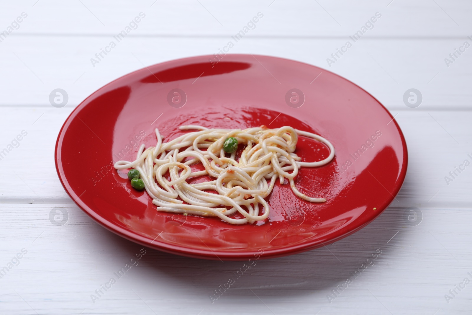 Dirty plate with spaghetti, peas and tomato sauce on white wooden table, closeup Photo of Dirty plate with spaghetti, peas and tomato sauce on white wooden table, closeup