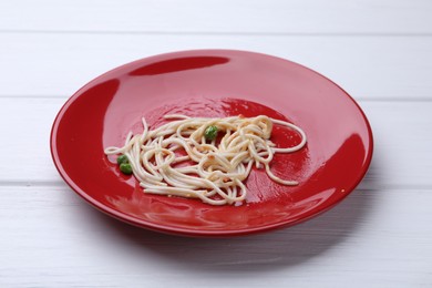 Photo of Dirty plate with spaghetti, peas and tomato sauce on white wooden table, closeup