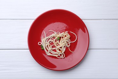 Photo of Dirty plate with spaghetti, peas and tomato sauce on white wooden table, top view