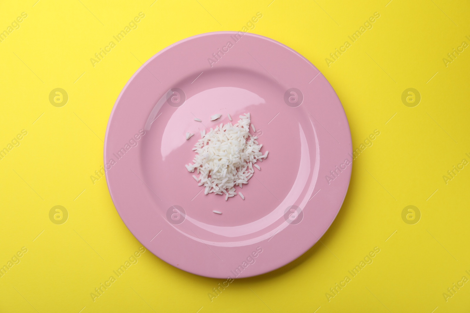 Plate with cooked rice on yellow background, top view Photo of Plate with cooked rice on yellow background, top view